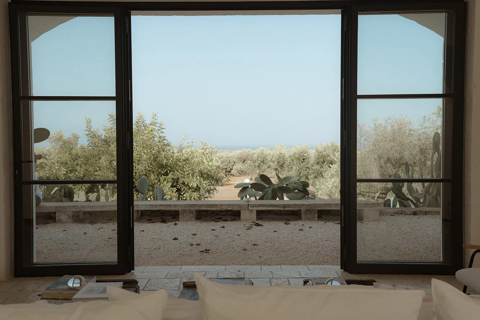The quiet luxury of Masseria Moroseta — morning light pouring through open doors, olive groves stretching to the sea, and the stillness that invites you to slow down and be fully here.