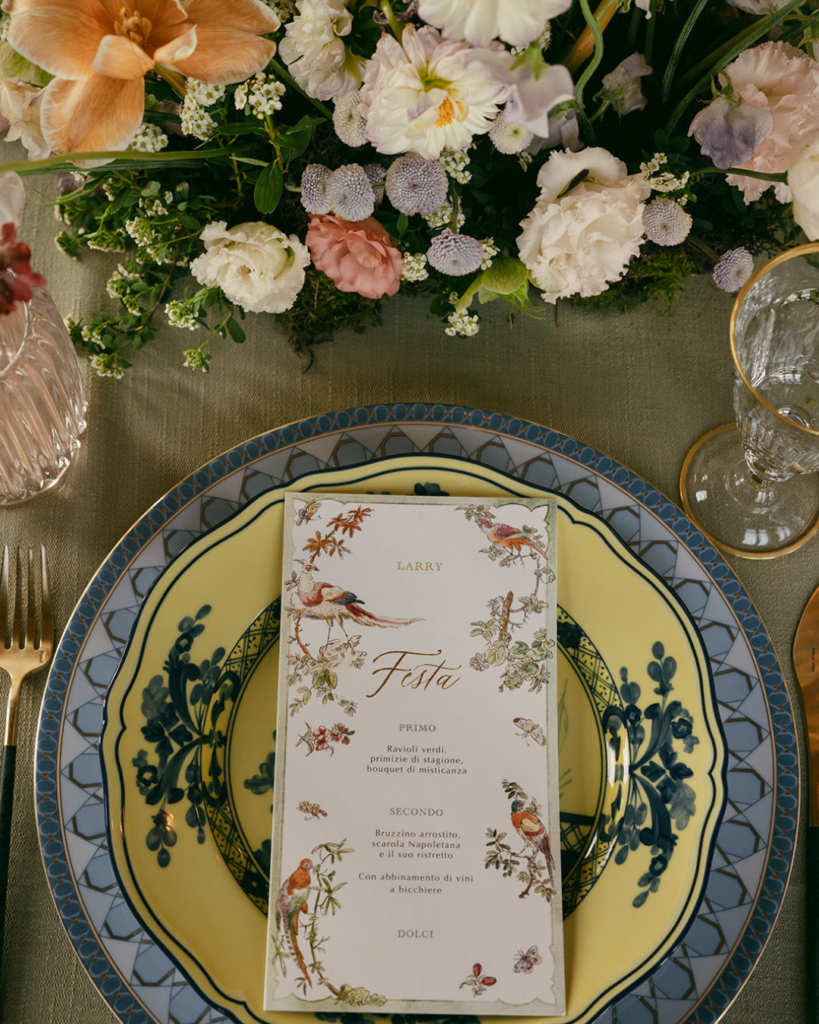 Place setting at Villa Corsini Florence with printed menu, patterned plate, floral arrangement, and glassware on reception table