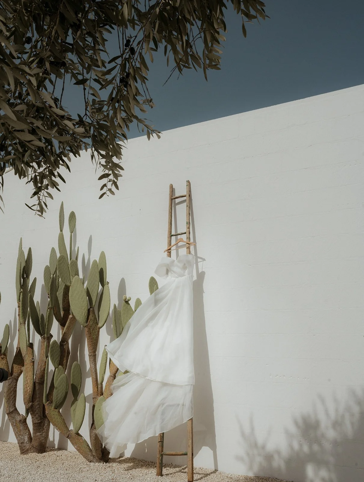 Eva Lendel Wedding gown blowing in the wind on the minimalist wall of masseria Moroseta