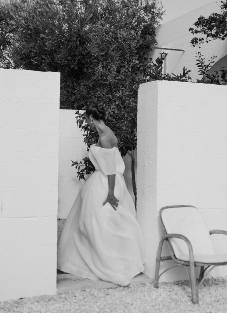 Bride in Eva Lendel wedding gown walking between white walls at Masseria Moroseta in Puglia Italy