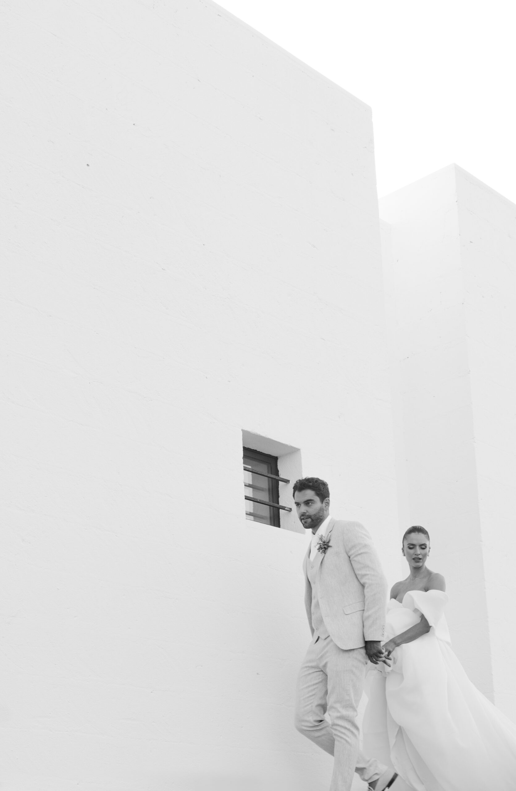 Bride and groom walking along white wall at Masseria Moroseta in Puglia Italy