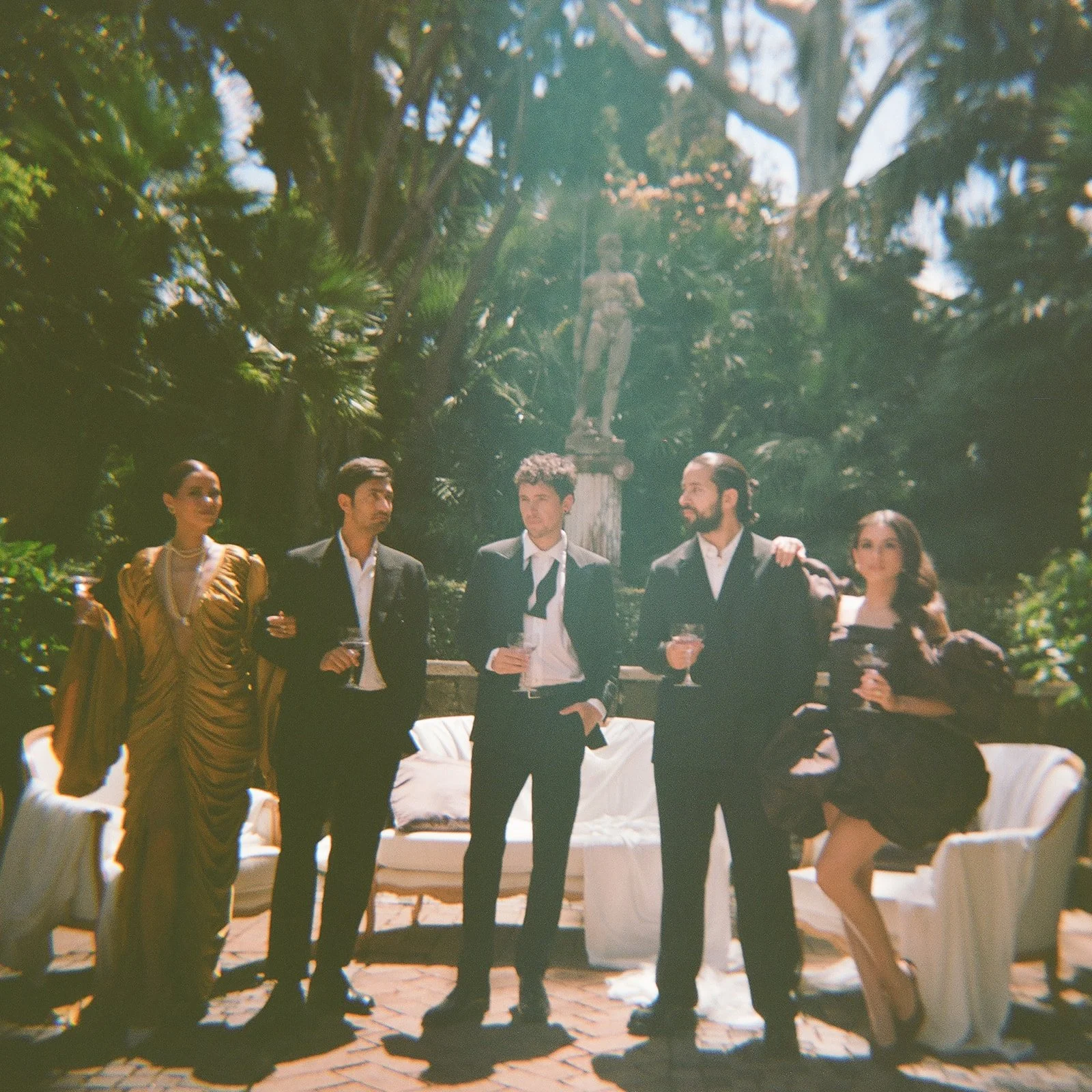  A vintage-inspired shot of the groom and guests mingling during cocktail hour. The soft focus and warm tones, along with a subtle light leak, give it a nostalgic, dreamy feel—like a fleeting memory. It’s relaxed, warm, and full of quiet moments you don’t usually see. 