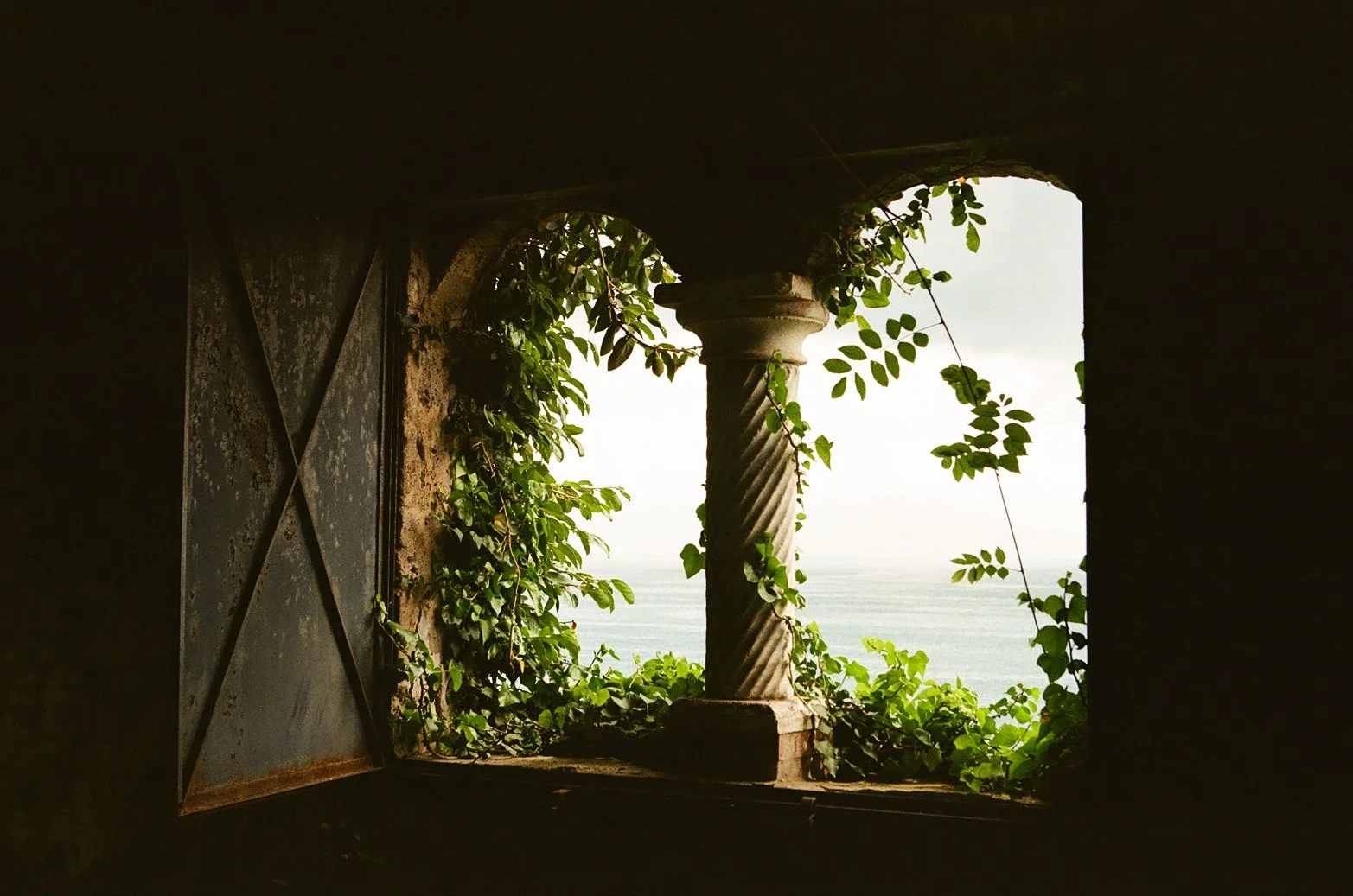  Framed by the weathered stone and twisted column of Villa Astor, the Tyrrhenian Sea stretches quietly into the horizon. Ivy spills into view like a secret, the kind you only discover when you slow down long enough to notice. Captured on Leica M7 35mm film for a timeless, tactile sense of place.   