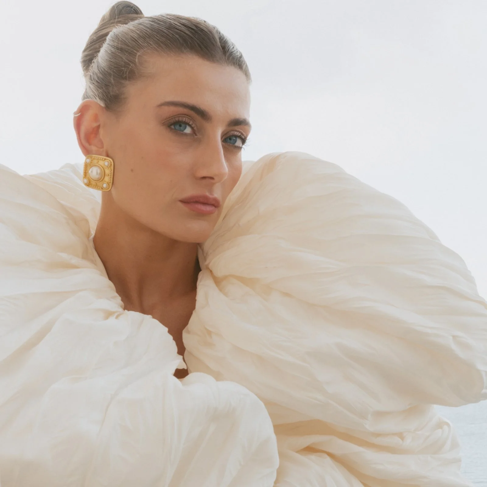  The kind of beauty that doesn’t ask for attention — it simply holds it. Her gaze steady, framed by folds of silk that feel more like clouds than fabric, golden pearls catching the last of the afternoon light. 