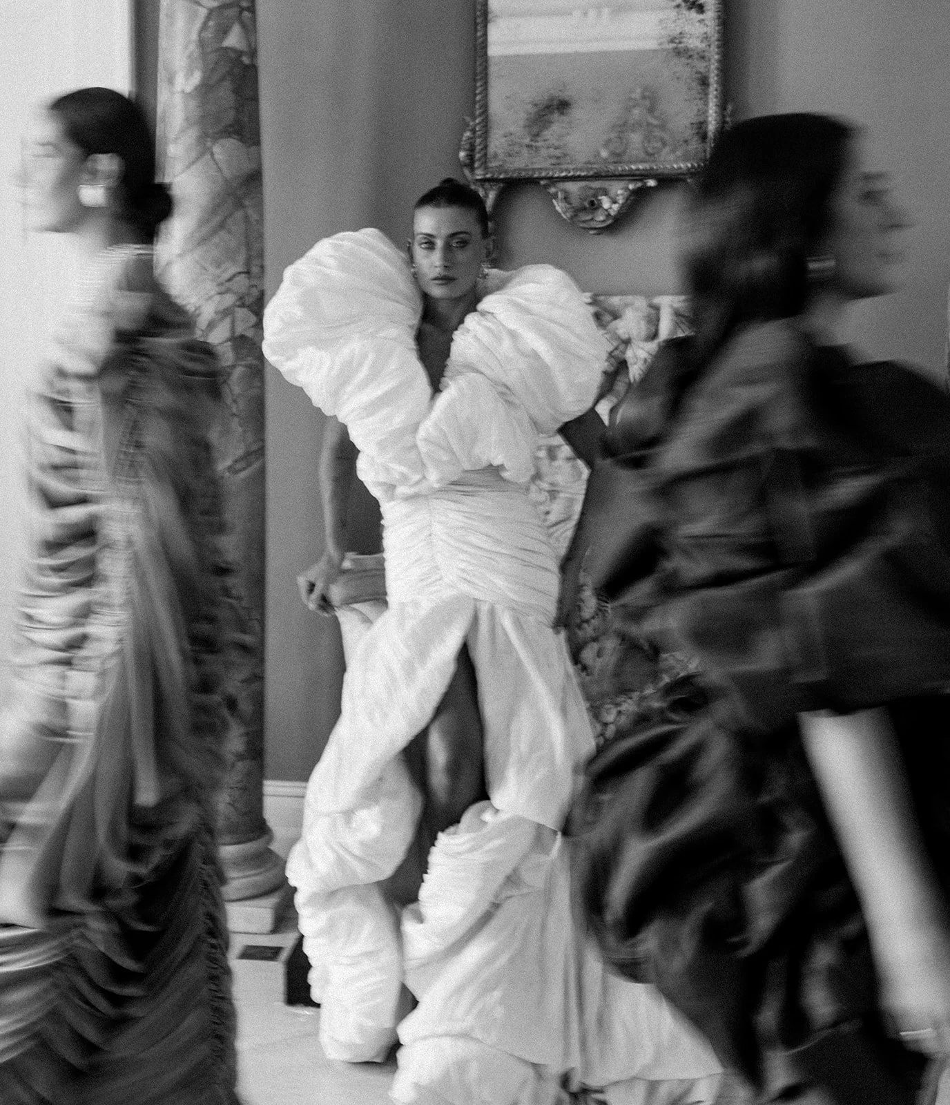  A moment caught between motion and stillness — she stands rooted in quiet command, the sculptural folds of her gown echoing the marble and history around her, while others blur past like fleeting thoughts. 