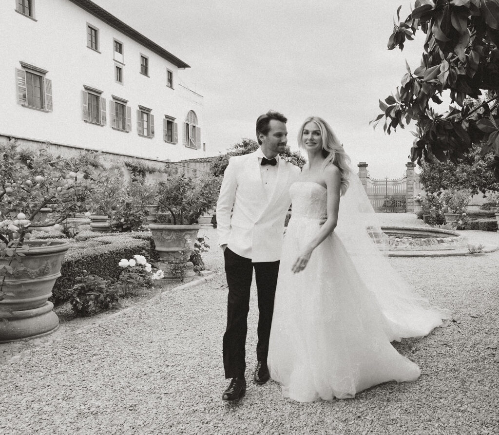 A Tuscany Wedding Styled at Villa Corsini: Timeless Editorial Inspiration in Italy Bride and groom walking through the gardens at Villa Corsini in Florence, Italy during an editorial black and white wedding portrait session.