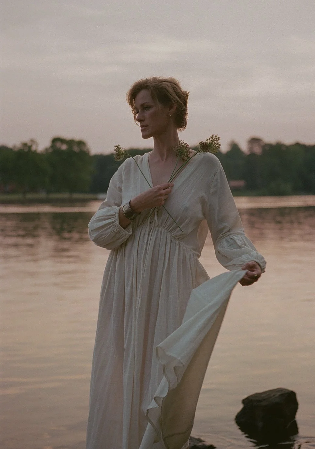  At golden hour by the lake, Krystallin holds wildflowers to her chest — the soft linen of her dress mirroring the stillness of the water. This moment felt like a quiet offering, a breath between movements, where light and presence aligned. 