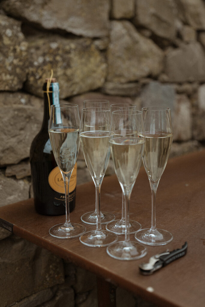 Prosecco glasses and bottle on a rustic stone table at Monteverdi Tuscany during a wedding welcome dinner.
