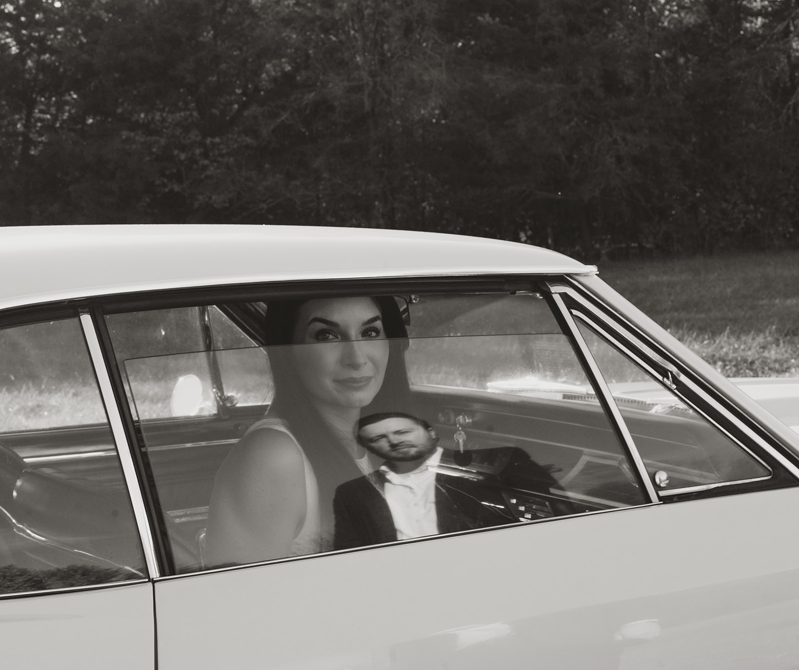 : Reflection of a man in a car window as a woman looks through the glass, captured in black and white on film.