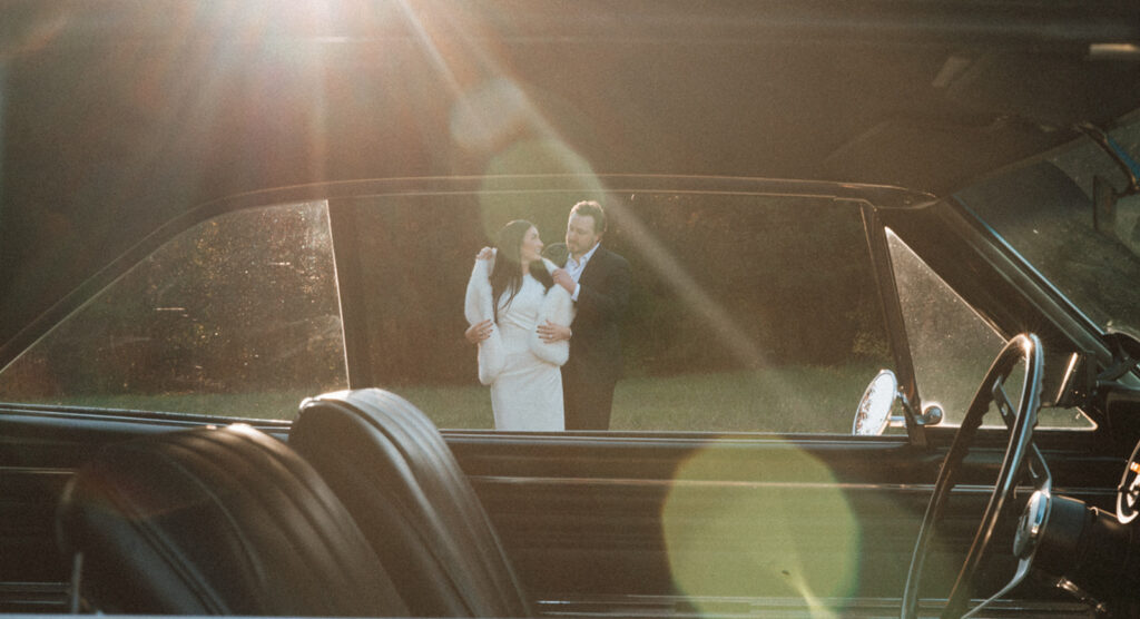 Couple dancing in golden light, framed through the window of a vintage car, captured during an editorial film-inspired couples session near Charlotte.