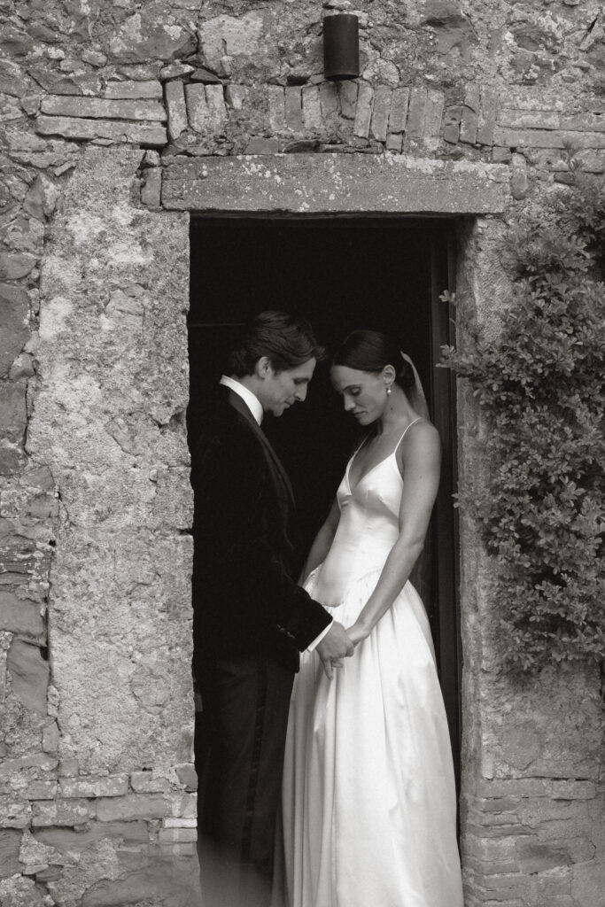 A Timeless Monteverdi Tuscany Wedding Bride and groom standing in stone doorway at Monteverdi Tuscany in black and white
