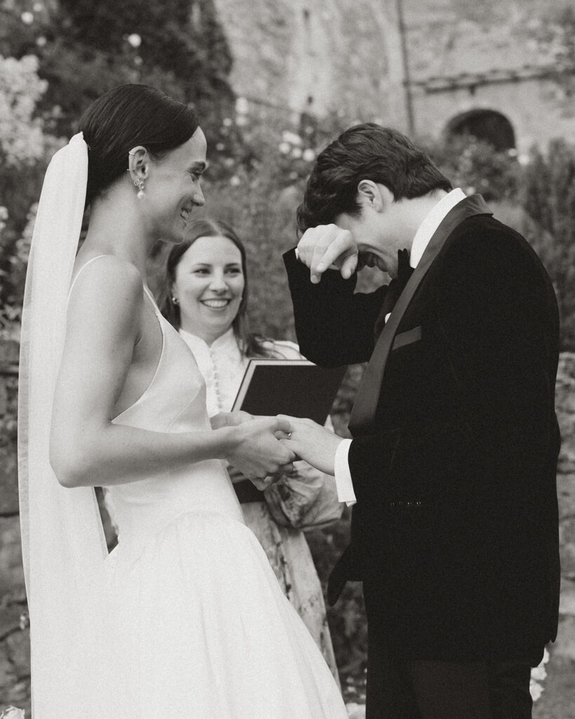 Bride in Danielle Frankel gown and Jane Rhyan The Collection veil holds hands with groom in black velvet tuxedo during emotional vows at Monteverdi Tuscany.