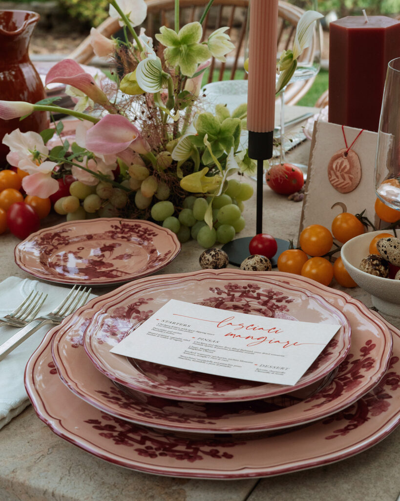 Monteverdi Tuscany wedding tablescape with terracotta pitcher, candlelight, and layered Italian plates in blush and red floral design.
