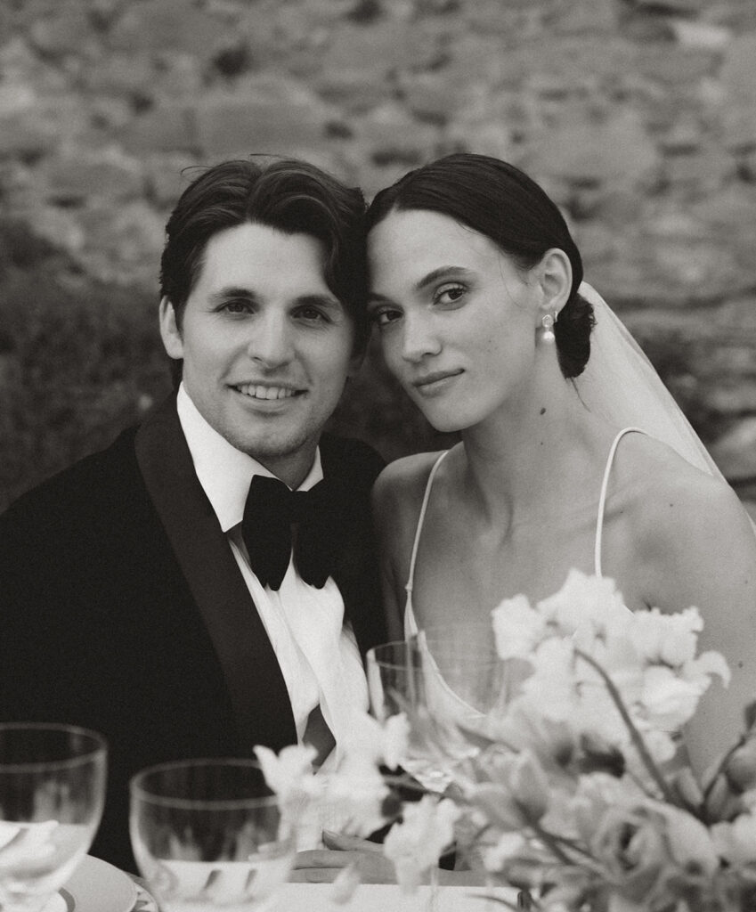 Black-and-white portrait of bride and groom seated at the wedding dinner at Monteverdi Tuscany.